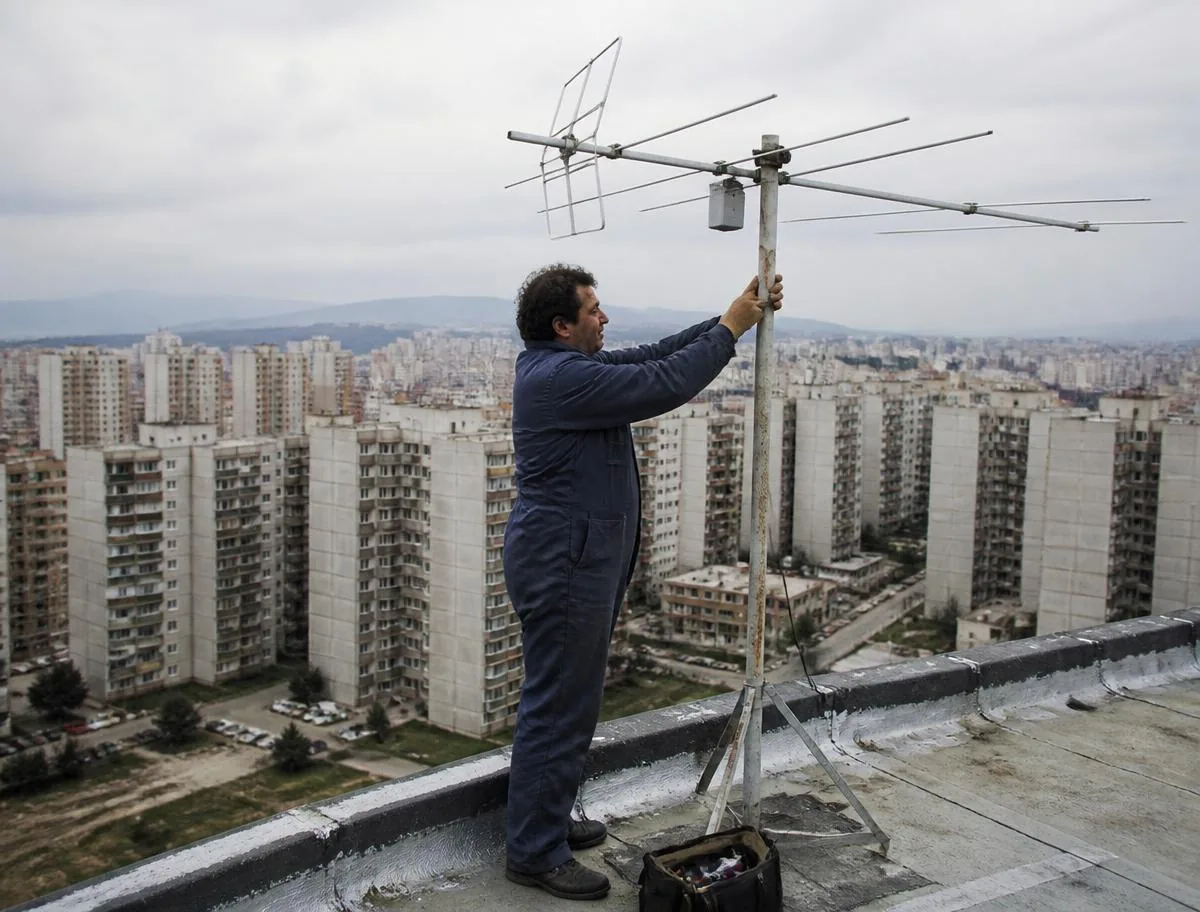Antenista ajustando una antena TDT en la azotea de un bloque de viviendas de Hospitalet de Llobregat